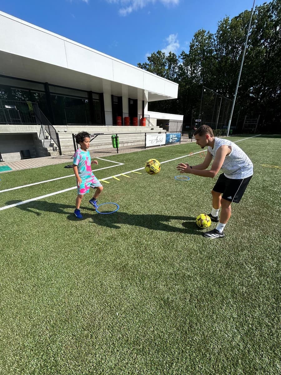 Coach werkt één-op-één met een jonge speler aan een looptechniek-oefening